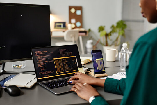 Closeup of female QA engineer typing on keyboard while using computer at workplace in office, copy space