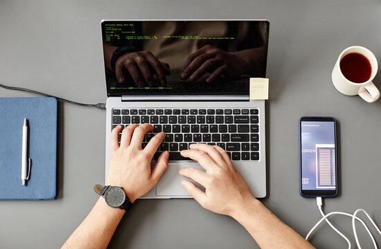 Minimal Top View Of Unrecognizable Man Using Laptop And Writing Code At Grey Workplace Desk