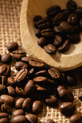 A scattering of coffee beans on a dark burlap background.
