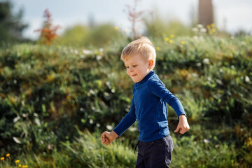 Little boy running down a meadow in a beautiful landscape in summer, very light and happy scene.