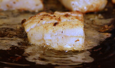Saftiges Fischfilet brutzelnd in einer Pfanne