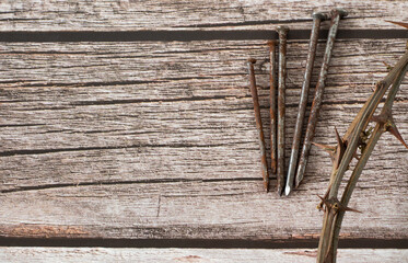 Thorn crown and rusty nails on a wooden background with copy space. Top view. Crucifixion, death,...