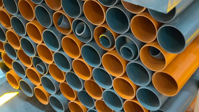 Stack of new plastic pipes in gray and orange for the sewerage system of the house. Shot in motion
