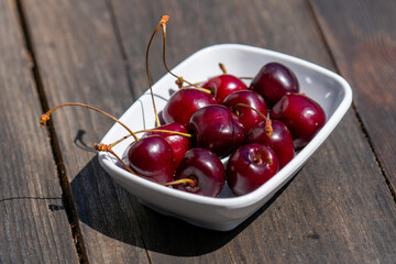 Selective focus shot of a plate of cherries on wooden table.