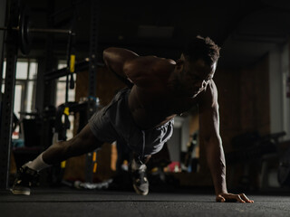 African american man doing one arm push ups in the gym. 