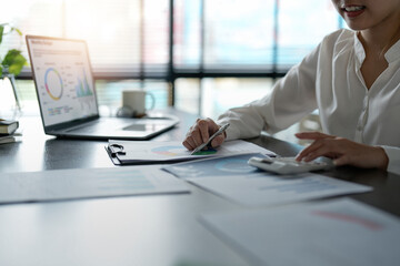 Business accounting concept, Business bookkeeper woman using calculator with computer laptop,...
