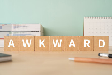 「AWKWARD」と書かれた積み木が置かれたデスク