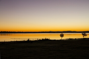 Fence extending into lake at sunrise