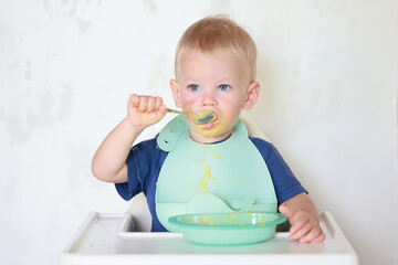 kid eats with a spoon and learns by himself