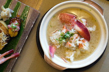Lobster Nabe in ceramic pot served with sushi set on the table. Top view