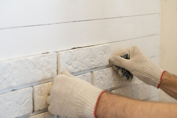 Professional Builder gluing decorative tile on wall. worker mounts decorative brick on wall