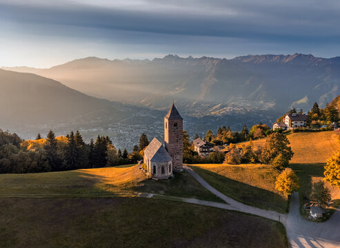 Hafling, Italy - Aerial view of the mountain church of St. Catherine (Chiesa di Santa Caterina) near Hafling - Avelengo on a warm autumn sunset with the Italian Dolomites in South Tyrol at background