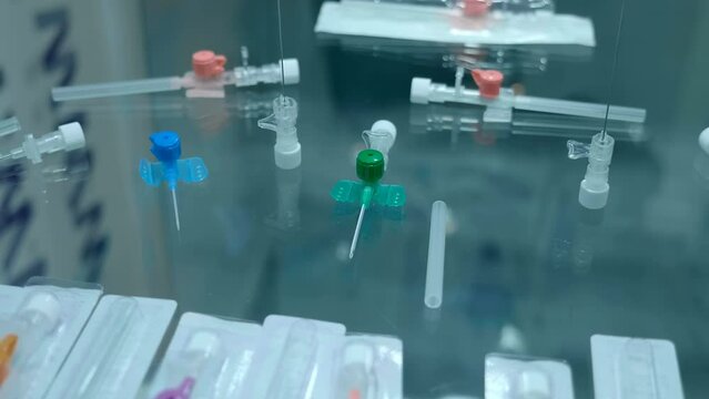 New samples of medical peripheral intravenous catheters of various sizes and purposes on a glass shelf at the exhibition of medical innovations. Closeup. Shot in motion