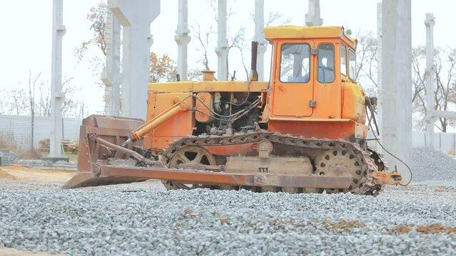 Yellow bulldozer works at a construction site. The bulldozer levels the layer of soil. Yellow bulldozer at the construction site. Bulldozer at the construction site. Heavy construction equipment