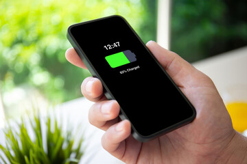 man hand holding phone with charged battery on the screen