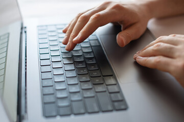 hands on laptop keyboard and phone in hand