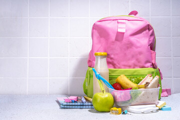Healthy school lunch box: sandwich, vegetables, fruit, nuts and yogurt with school kids supplies,...