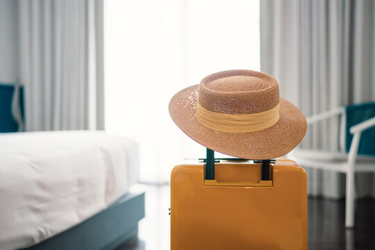 Suitcase or luggage bag with hat in a modern hotel room - relaxing time, holidays, weekend and traveling concept. copy space.