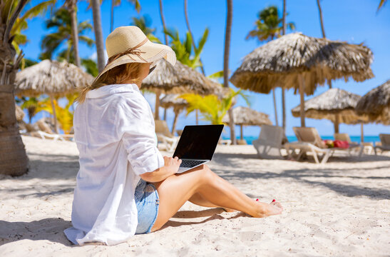 Woman working with laptop computer on tropical beach