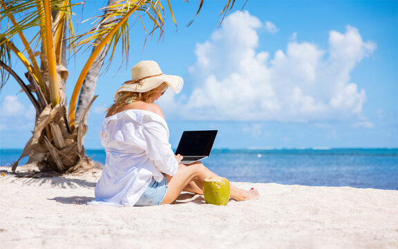 Woman working with laptop computer on the tropical beach, concept of working anywhere
