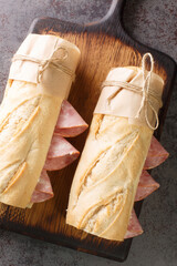French sandwich crusty baguette, lightly salted butter and thinly sliced ham, ideally Jambon de Paris closeup on the wooden board. Vertical top view from above - obrazy, fototapety, plakaty