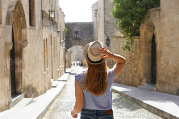 Tourism in Rhodes, Greece. Back view of traveler girl goes down the Street of the Knights of Rhodes...