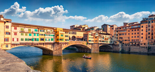 Fototapeta na wymiar Sunny summer view of medieval arched river bridge with Roman origins - Ponte Vecchio over Arno river. Wonderful evening cityscape of Florence, Italy, Europe. Traveling concept background.