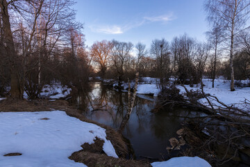 Winter landscape, trees near the river against the backdrop of sunset.