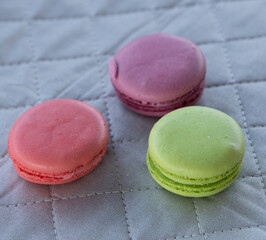 Macarons three cookies on a cloth napkin background. Multicolored french pasta for breakfast.