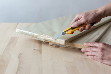 Fototapeta na wymiar Unpacking a furniture board with a knife. Unpacking a wooden board.