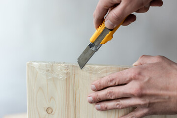 Unpacking a furniture board with a knife. Unpacking a wooden board.