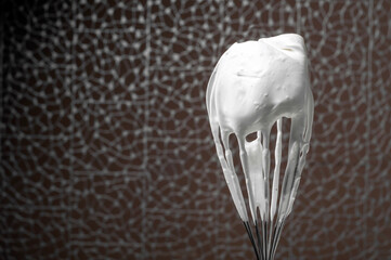 whisk with whipped cream or whipped white on a brown background, horizontal shot, copy space.