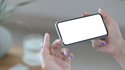 Close up view woman holding smart phone in horizontal position with empty screen for graphics display montage