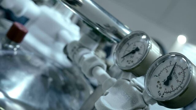 The arrow of the pressure gauge of compressed gas fluctuates due to the flow of this gas, and the pipelines are covered with frost due to a large temperature difference. Closeup