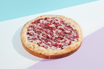 Italian pizza with fruit and berries on coloured background. Sweet pizza with bananas, berries and sauce in minimal style on blue color. American pizza delivery concept with color backdrop.