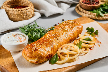 Meat pie with greens and onion on wood plate. Eastern food - beef pie with sesame. Eastern pastry with Minced meat.