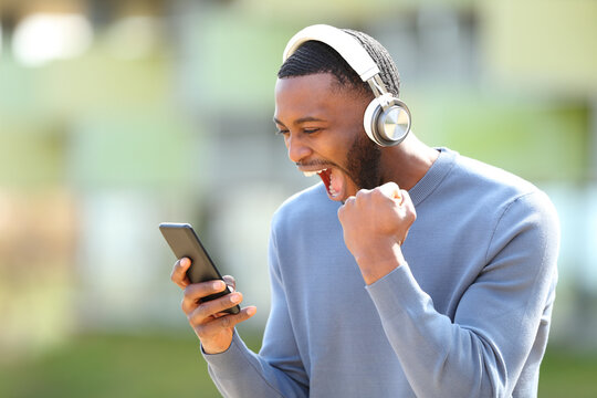 Excited man with black skin checking music on phone