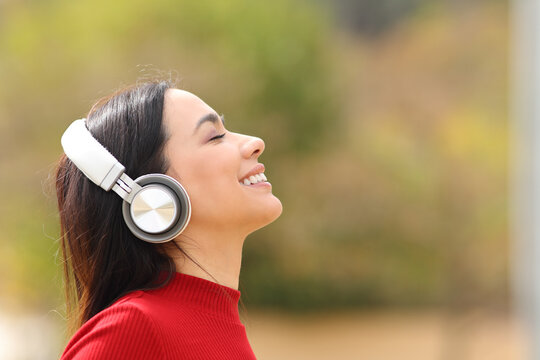 Happy woman listening to music in a park wearing headphones