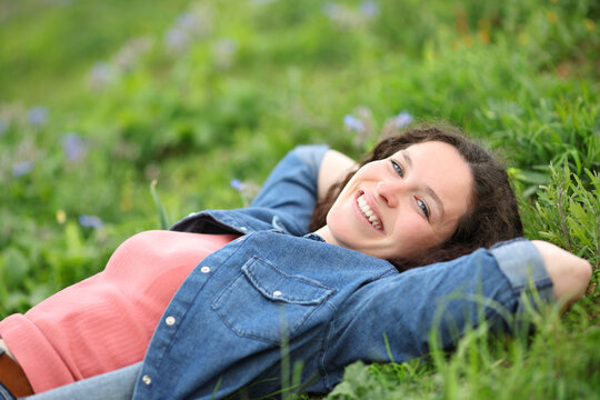 Happy woman relaxing on the grass looking at camera