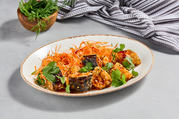 Traditional chinese dish - crispy eggplant with sweet chili sauce. Vegan food - stir fried eggplant with vegetables. Crispy aubergine with chilli sauce on ceramic plate. Modern asian food.