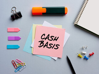 The word cash basis written on a notepaper on business office desktop.