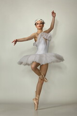 Beautiful girl ballerina in a white tutu and pointe shoes posing on a white background