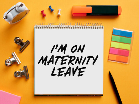 The message I am on maternity leave written on a notebook on business office desktop.
