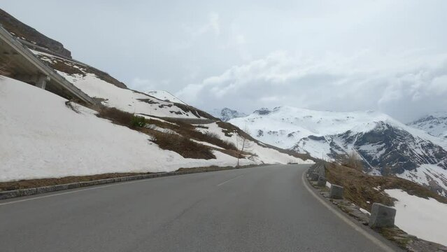 POV of curvy ride over steep high alpine road at pass next to Grossglockner in Austria with snow on embankments