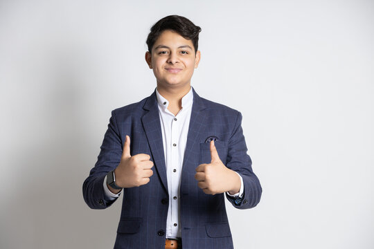 Portrait of a confident young indian teenager boy wearing suit do thumbs up with both hands isolated on white background. all the best