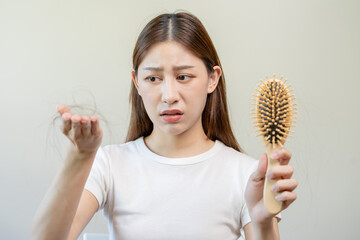 Serious, worried asian young woman, girl holding comb, show her hairbrush with long loss hair...