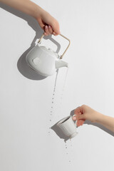 teapot pouring tea into  cup, on white background