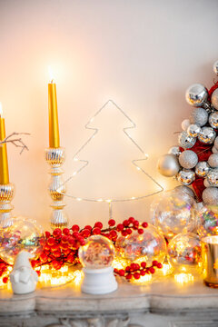 Red Holly berries with burning candles on marble fireplace at home