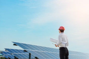 Young man engineer in white shirt and red safety helmet holding a tablet and project paper plan and...