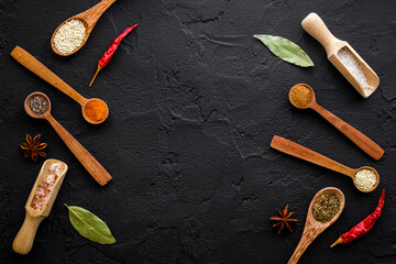 Variety of colorful spices and herbs in wooden spoons on kitchen table, top view